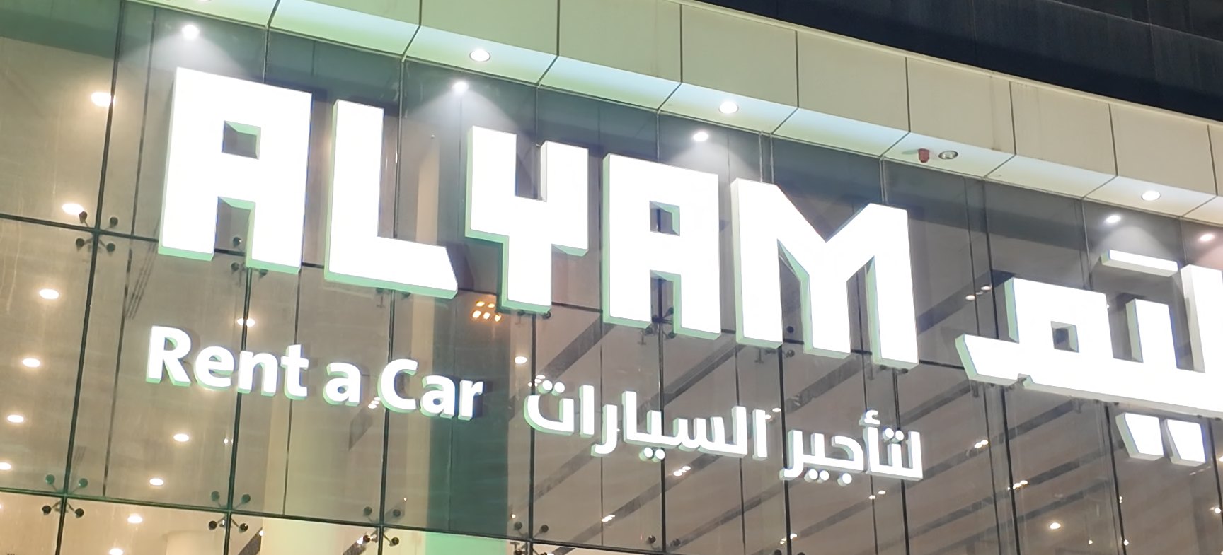 The Alyam Rent a Car sign on a branch at night